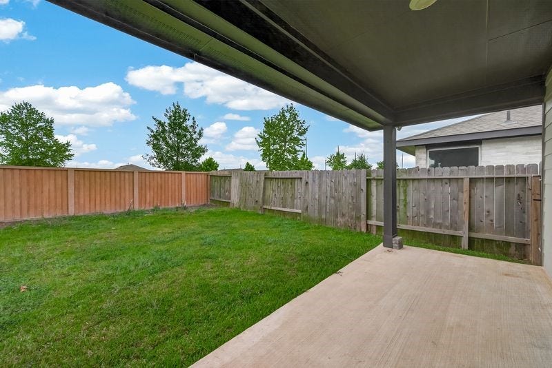7523 Keystone Blossom Trail, Richmond, TX 77407 Covered patio overlooking a fully fenced backyard, offering a private outdoor setting with open green space and room for relaxation or entertaining.