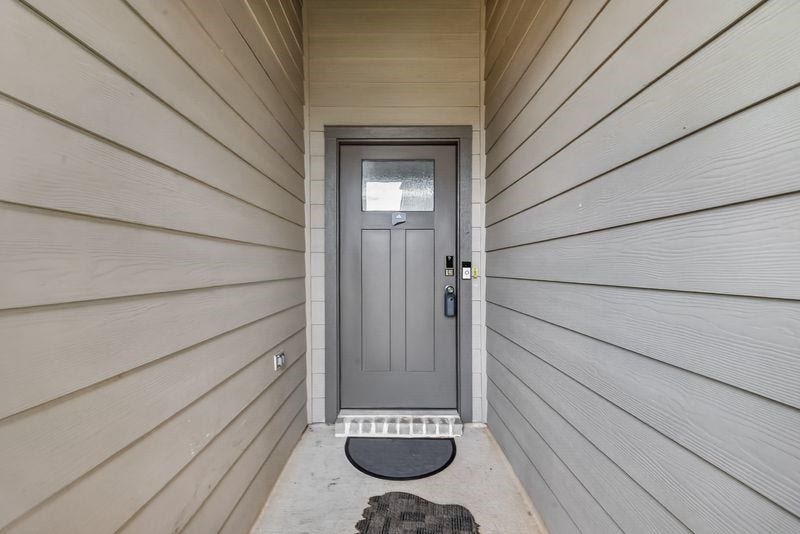 7523 Keystone Blossom Trail, Richmond, TX 77407 Covered entryway with a recessed front door, offering a sheltered approach framed by clean siding lines and a defined threshold.