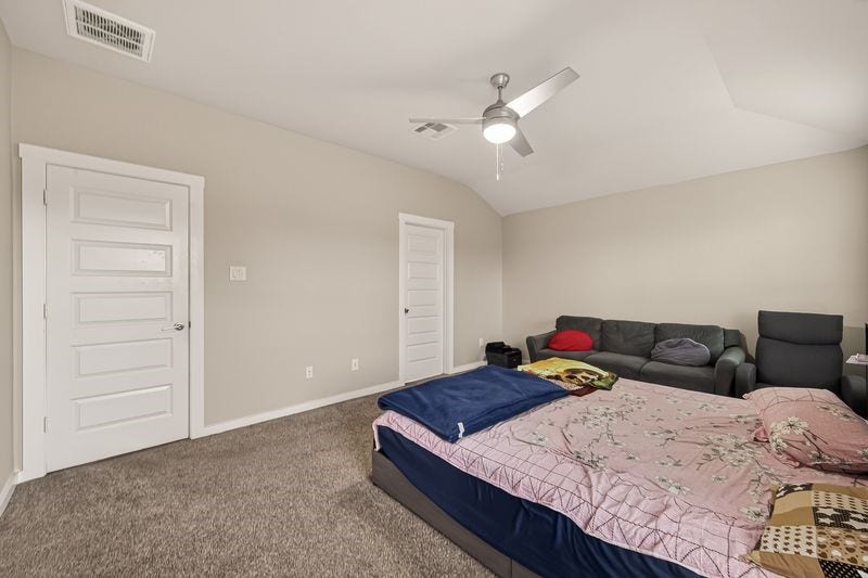 7523 Keystone Blossom Trail, Richmond, TX 77407 Alternate angle of the primary suite showcasing expansive wall space, closet access, and a well-proportioned layout beneath a central ceiling fan.