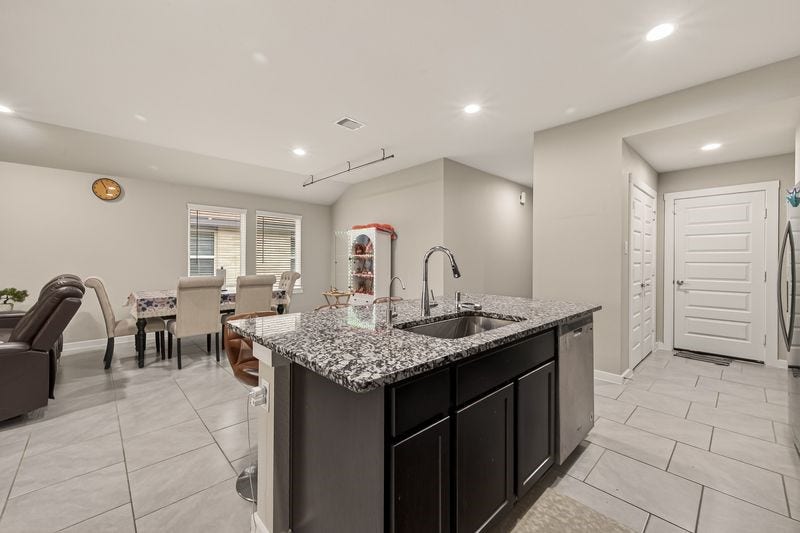 7523 Keystone Blossom Trail, Richmond, TX 77407 Alternate angle of the kitchen island highlighting the sink placement, surrounding counter space, and direct access toward the entryway and adjacent living areas.