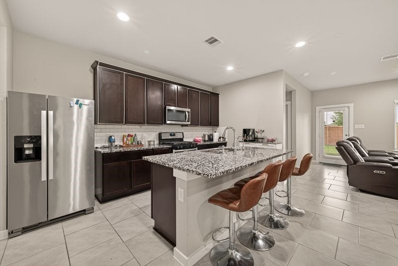 7523 Keystone Blossom Trail, Richmond, TX 77407 Refined view of the central gathering area capturing the cohesive flow between seating, kitchen island, and adjoining spaces under consistent recessed lighting.