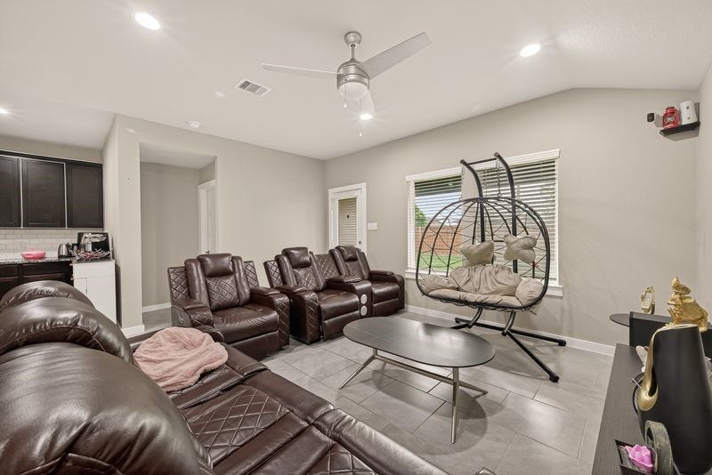 7523 Keystone Blossom Trail, Richmond, TX 77407 Spacious living area featuring a central ceiling fan, large window for natural light, and an open connection to the kitchen, creating a comfortable and airy gathering space.