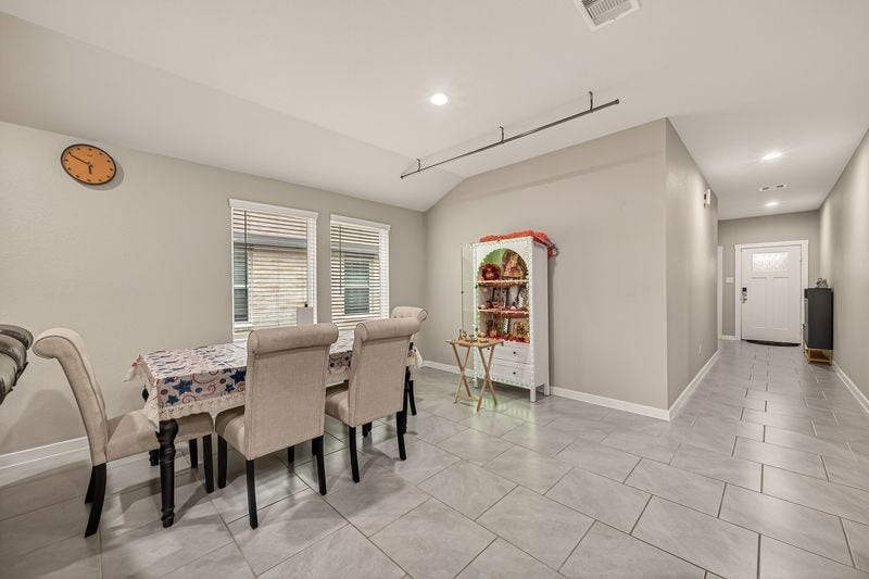 7523 Keystone Blossom Trail, Richmond, TX 77407 Reverse perspective from the dining space highlighting dual windows for natural light and a clear view back toward the entry corridor, enhancing the homes open flow.