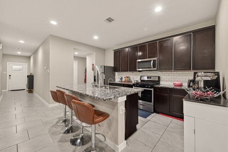 7523 Keystone Blossom Trail, Richmond, TX 77407 Slightly varied angle of the living space emphasizing the connection to the kitchen and dining areas, with continuous flooring and balanced lighting throughout.