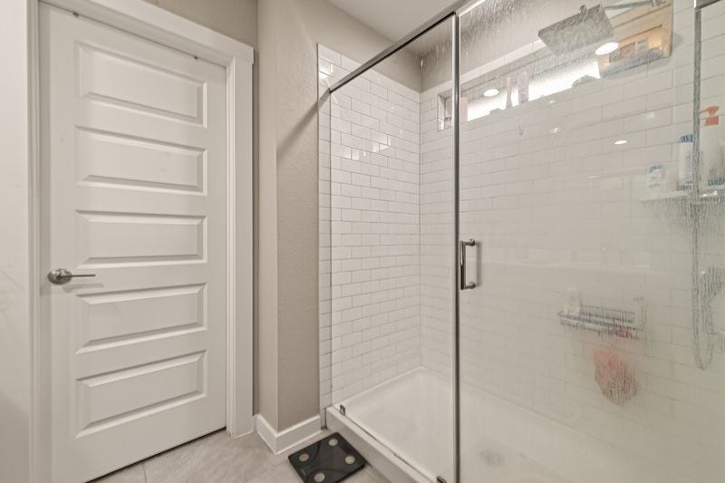 7523 Keystone Blossom Trail, Richmond, TX 77407 Refined view of the glass-enclosed shower featuring a tiled surround and clean, modern finishes, positioned conveniently within the primary bathroom layout.