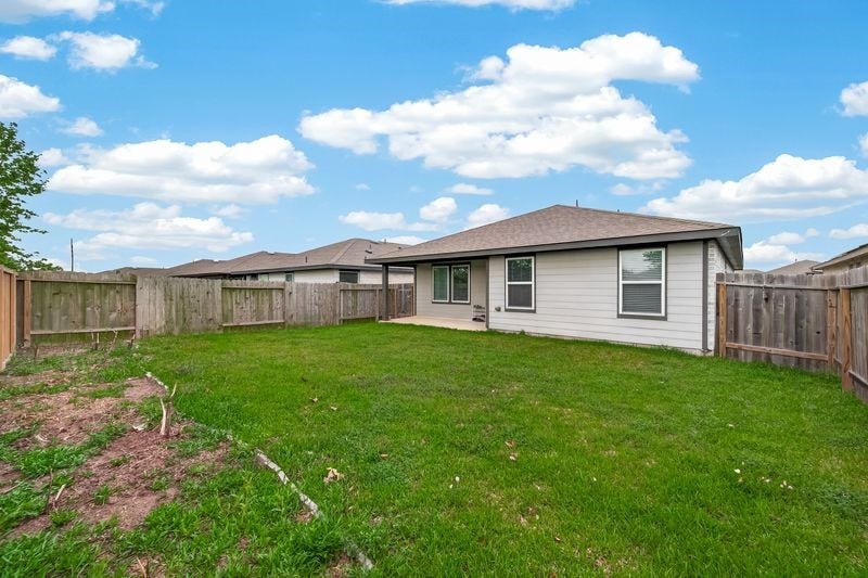 7523 Keystone Blossom Trail, Richmond, TX 77407 Angled rear exterior view capturing the depth of the backyard, side fencing, and the homes extended back elevation with consistent window placement.