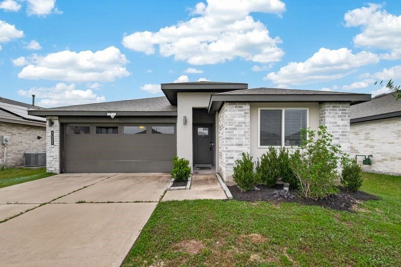 7523 Keystone Blossom Trail, Richmond, TX 77407 Clean-lined brick faade with a wide driveway leading to a two-car garage, complemented by a covered entry and neatly maintained landscaping that frames the front elevation.
