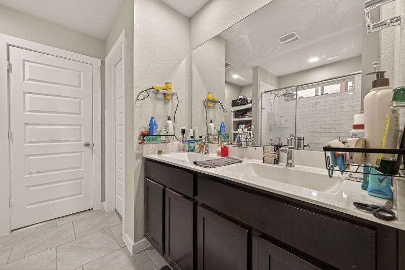 7523 Keystone Blossom Trail, Richmond, TX 77407 Alternate perspective of the primary bathroom highlighting the extended vanity, dual sinks, and wide mirror that enhances depth and brightness within the space.