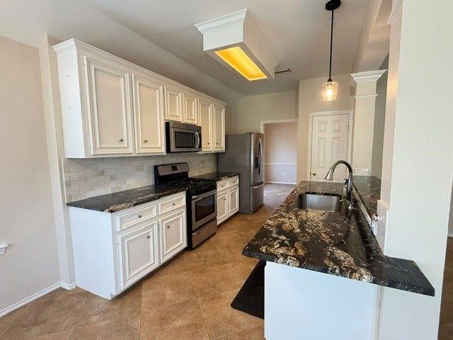 3511 Paigewood Drive, Pearland, TX 77584 Elegant kitchen featuring sleek granite countertops, stainless steel appliances, and classic white cabinetry, complemented by a chic pendant light fixture.