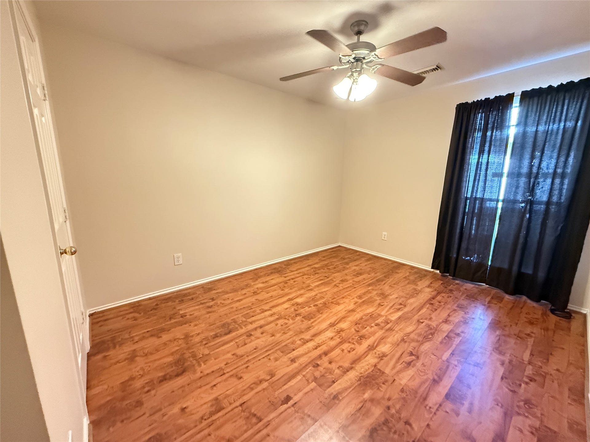 3511 Paigewood Drive, Pearland, TX 77584 Guest bedroom 3 featuring warm vinyl plank floors, a ceiling fan, and ample natural light through large windows with dark curtains.