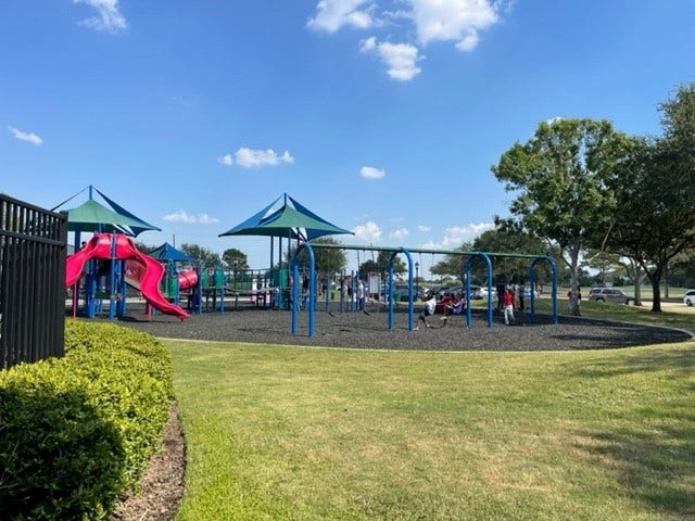 3511 Paigewood Drive, Pearland, TX 77584 Charming community playground featuring vibrant play structures, surrounded by lush green lawns and shady trees, perfect for family fun and outdoor activities.