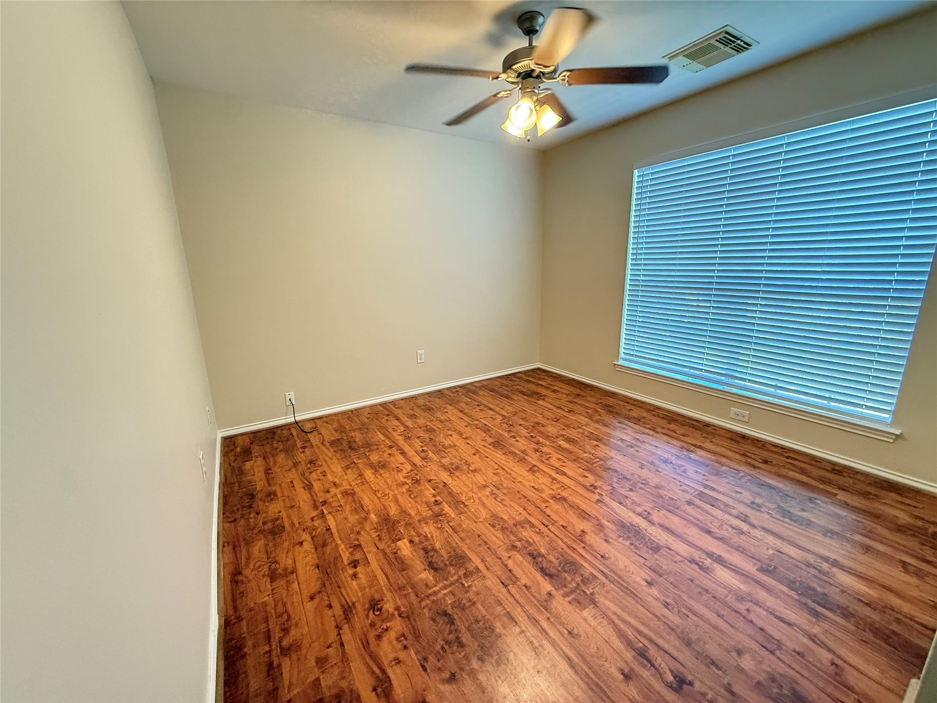 3511 Paigewood Drive, Pearland, TX 77584 Second bedroom featuring rich vinyl plank floors, a large window with blinds for ample natural light, and a ceiling fan for comfort.