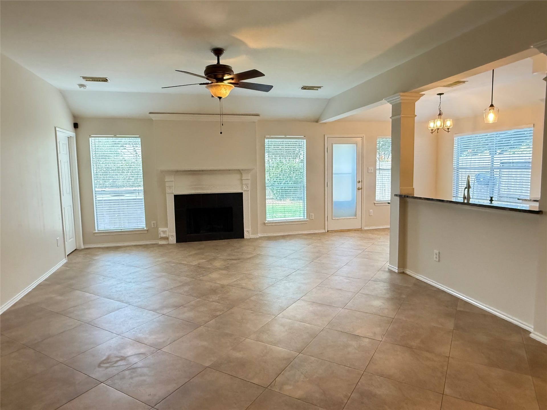 3511 Paigewood Drive, Pearland, TX 77584 Spacious living area with neutral tile flooring, a cozy fireplace, and abundant natural light from large windows. The open layout seamlessly connects to a modern kitchen, perfect for entertaining.