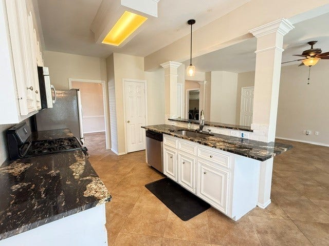 3511 Paigewood Drive, Pearland, TX 77584 Spacious kitchen featuring elegant granite countertops, modern stainless steel appliances, and a convenient breakfast bar, seamlessly flowing into an open living area with stylish ceiling fan accents.