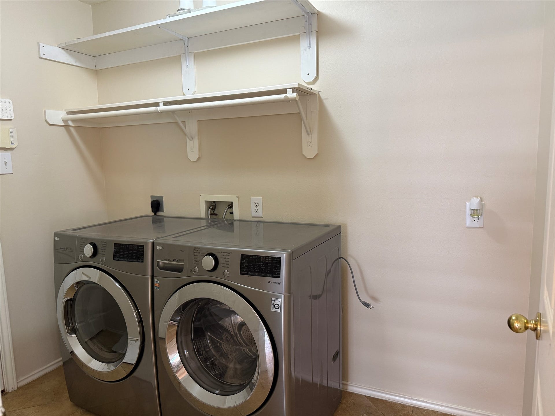 3511 Paigewood Drive, Pearland, TX 77584 Modern laundry room featuring sleek stainless steel washer and dryer units, complemented by ample shelving for storage and organization.