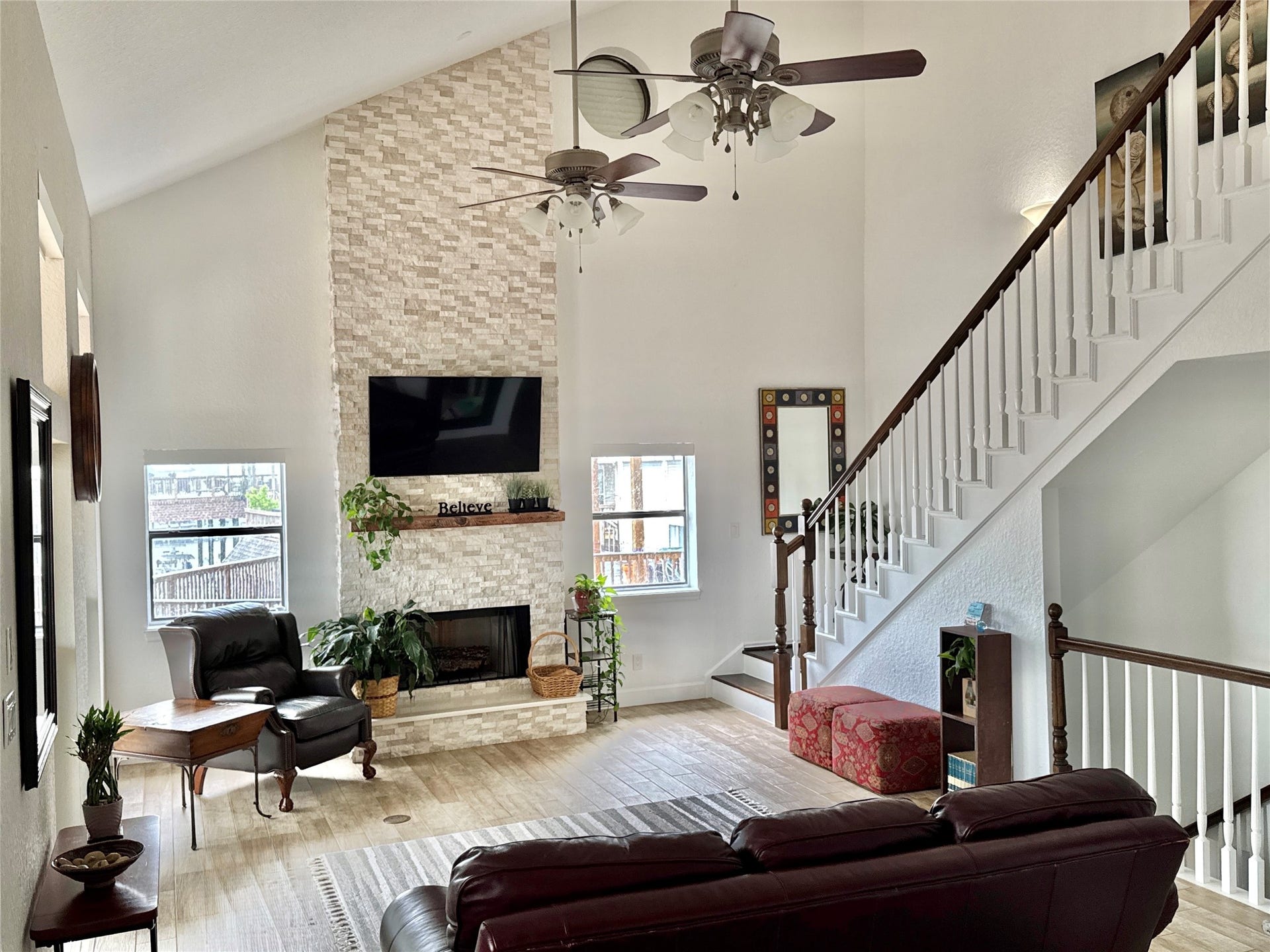 107 Bamaku Bend, Tiki Island, TX 77554 An open, expansive living area showcases the home's dramatic scale, anchored by a stone floor-to-ceiling wood-burning fireplace.