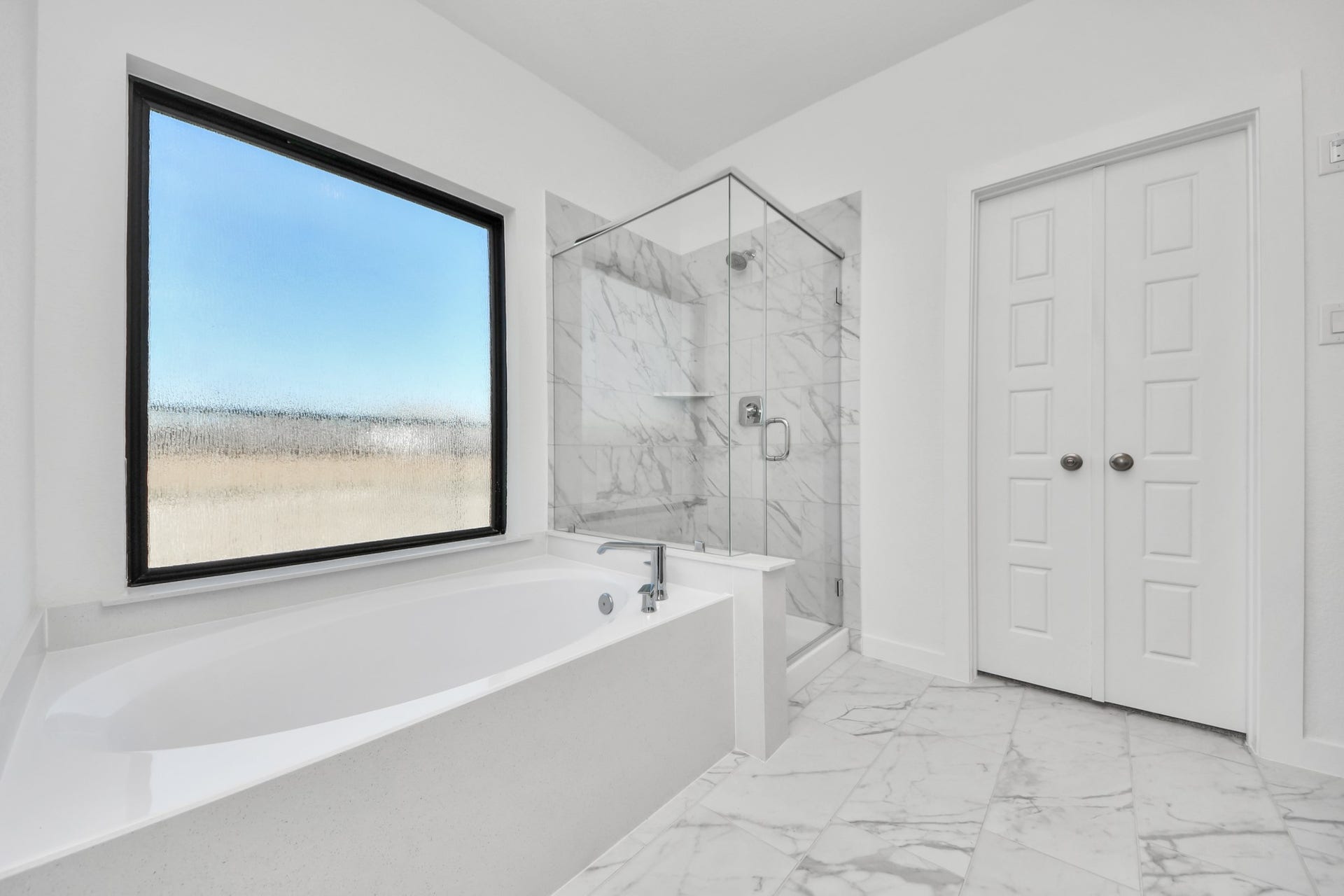 Indulge in a spa-like retreat within the confines of this primary bathroom. Delight in a spacious walk-in shower enveloped in stylish tile surround, unwind in a separate garden tub adorned with custom detailing. Sample photo of completed home with similar floor plan. Actual colors and selections may vary.