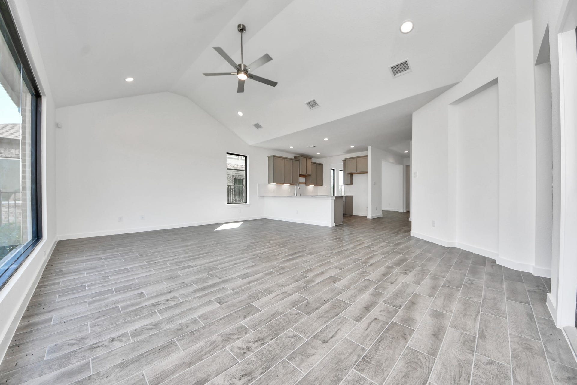 Family room flooded with natural light through the expansive windows.  The premium tile flooring adds a touch of luxury to the space, creating the perfect setting for relaxing moments and cherished gatherings with loved ones. Sample photo of completed home with similar floor plan. Actual colors and selections may vary.