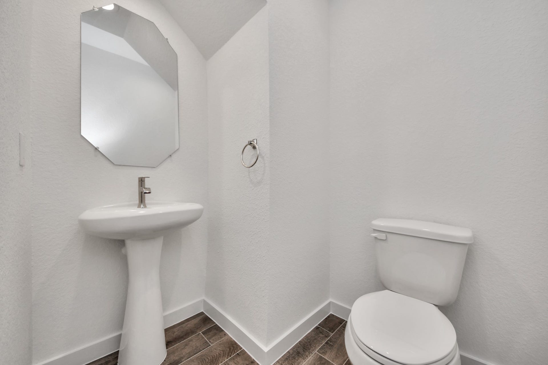 This half bathroom features a stylish pedestal sink, modern hardware, and bright recessed lighting, creating a sleek and inviting space. Sample photo of completed home with similar floor plan. Actual colors and selections may vary.