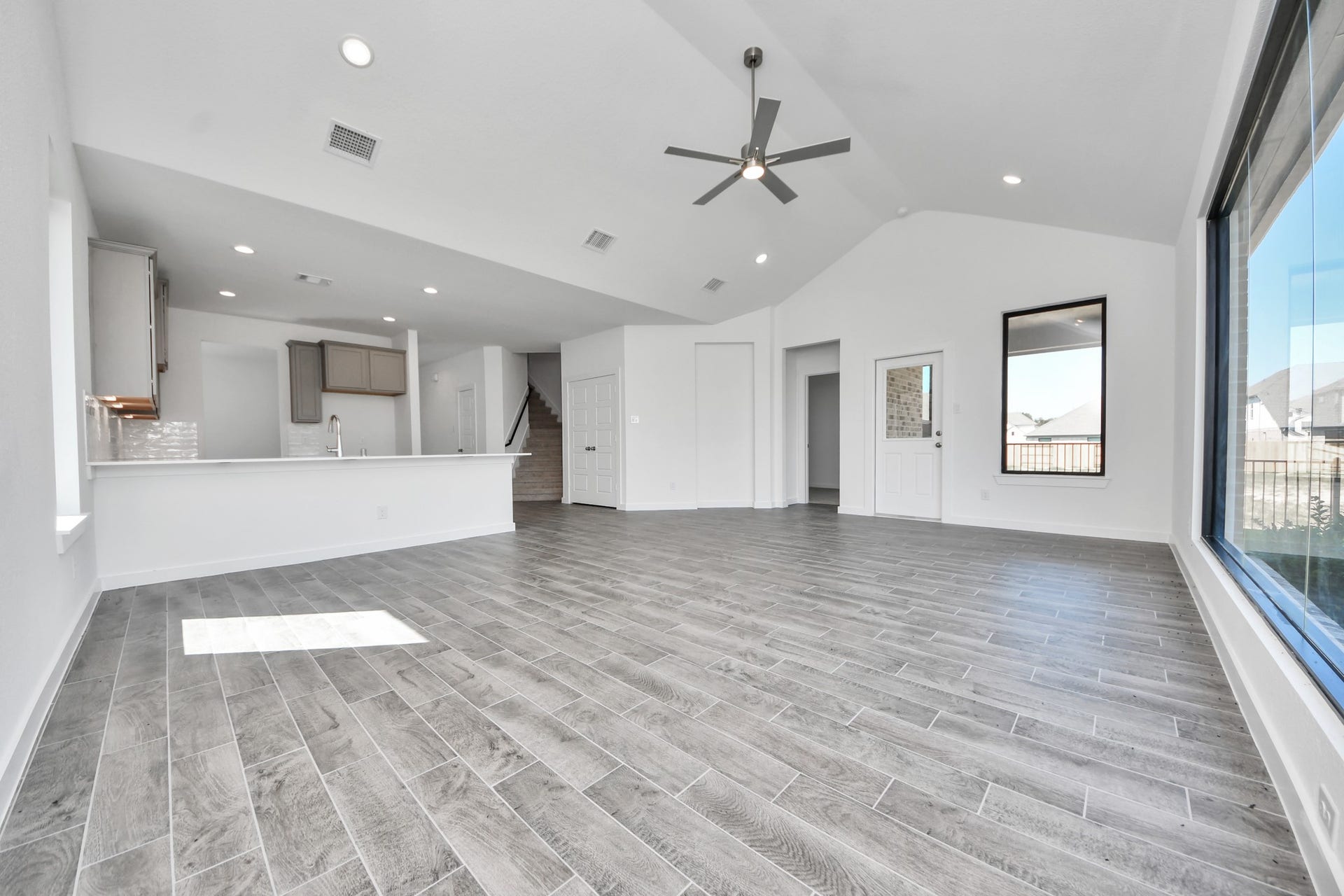 Gather the family and guests together in your lovely living room! Featuring soaring high ceilings, recessed lighting, ceiling fan, custom paint, gorgeous floors, and large windows that provide plenty of natural lighting throughout the day. Sample photo of completed home with similar floor plan. Actual colors and selections may vary.