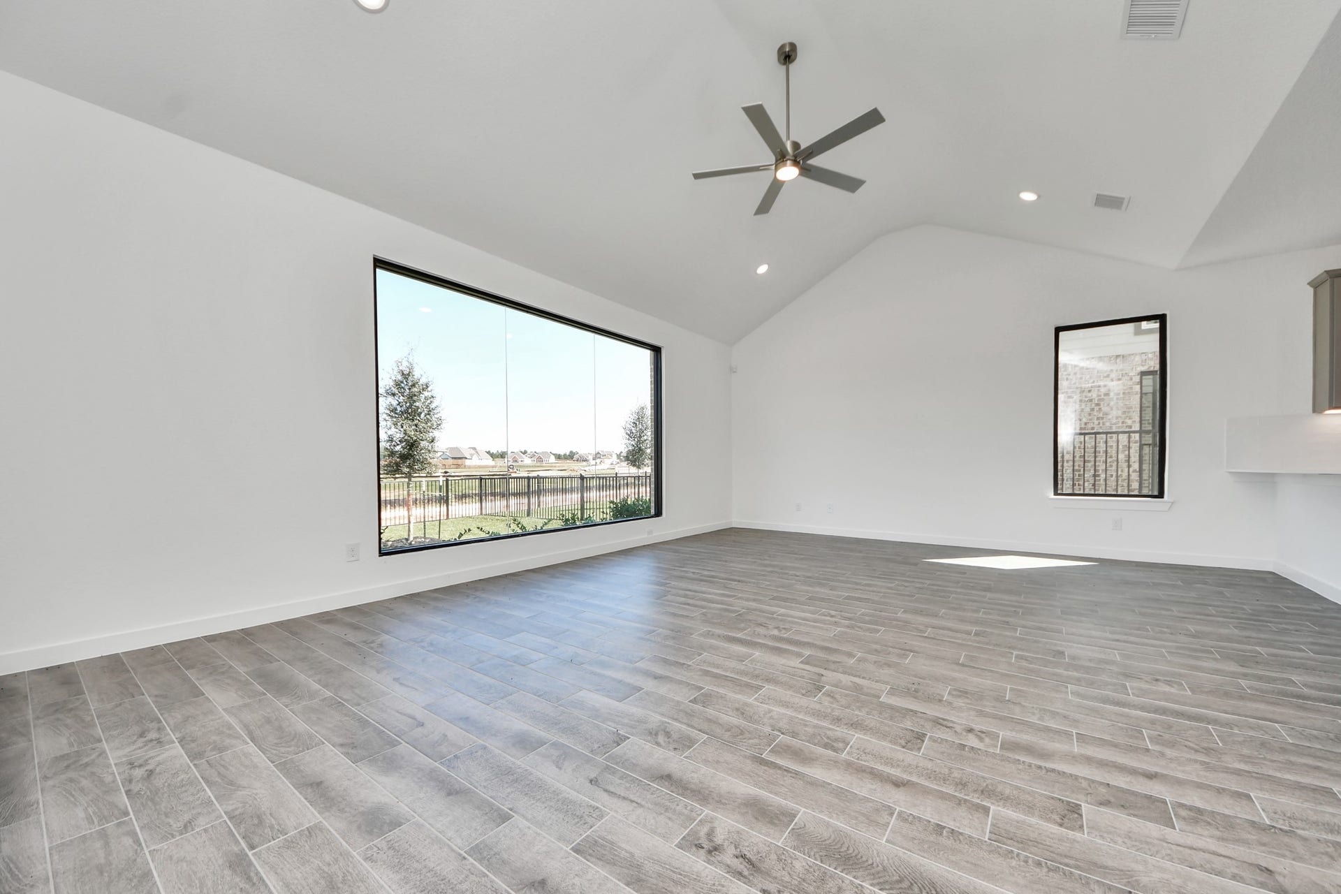 Relax and unwind in this inviting family room, illuminated by abundant natural light streaming in through tall windows, complemented by high ceilings and stunning flooring. Stay comfortable year-round with the gentle breeze from the ceiling fan, creating the perfect atmosphere for family gatherings. Sample photo of completed home with similar floor plan. Actual colors and selections may vary.