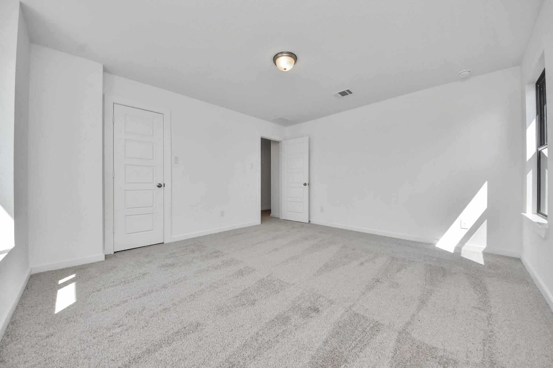 Secondary bedroom features plush carpeting, large windows that let in plenty of natural light, bright paint, and spacious closets. Sample photo of completed home with similar floor plan. Actual colors and selections may vary.