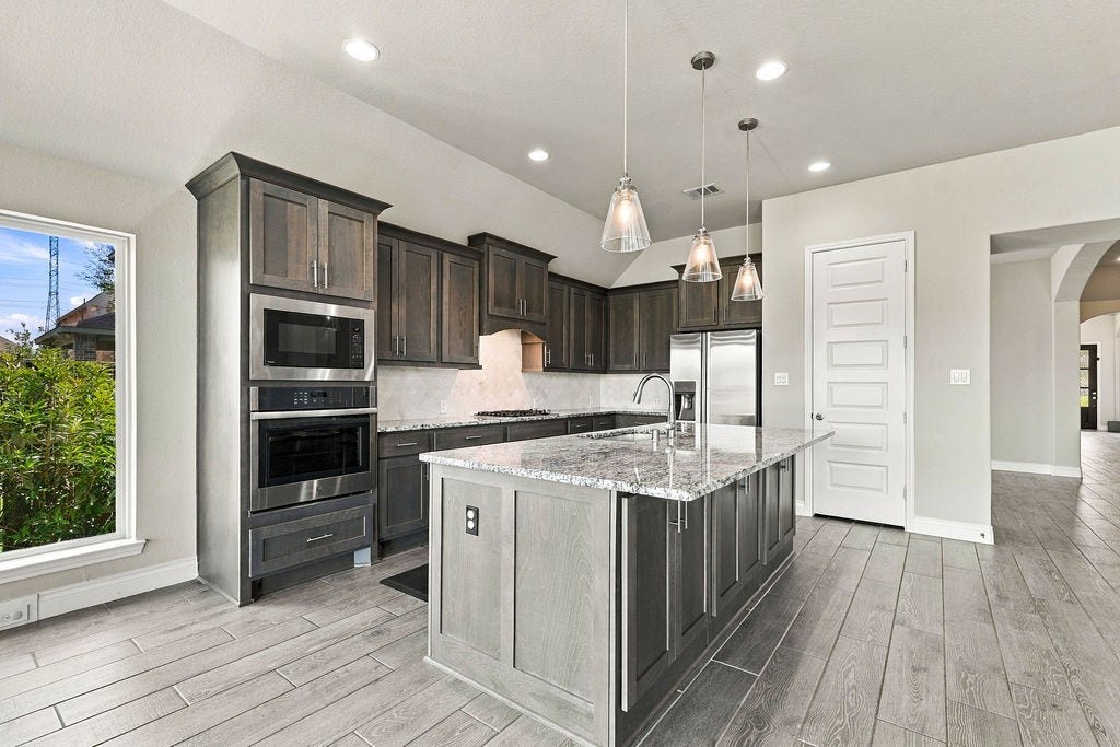 6914 Red Oak Drive, Katy, TX 77493 Stunning modern kitchen featuring sleek dark cabinetry, stainless steel appliances, and a spacious granite island with pendant lighting, perfect for culinary enthusiasts.