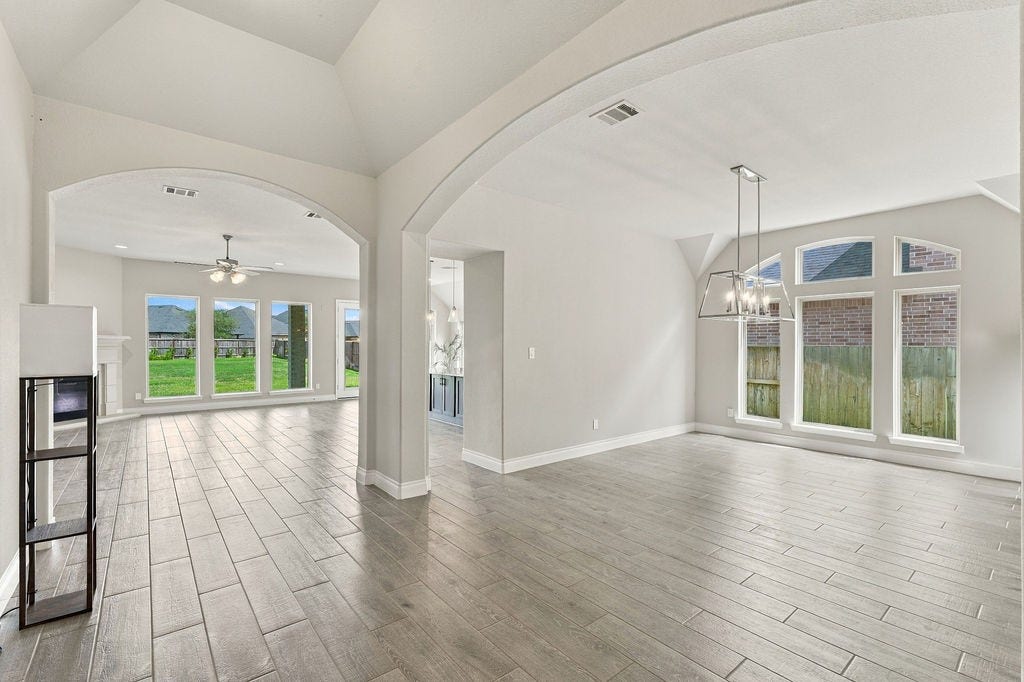 6914 Red Oak Drive, Katy, TX 77493 Spacious open-concept living area with elegant arched doorways, abundant natural light from large windows, and modern tile flooring throughout.