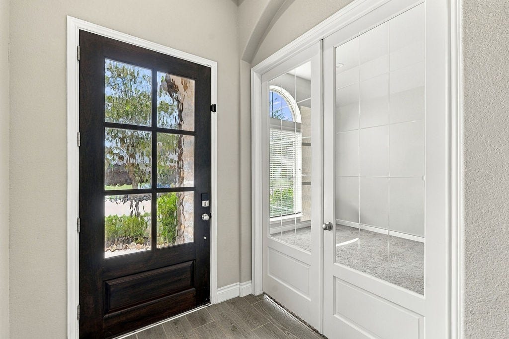 6914 Red Oak Drive, Katy, TX 77493 Inviting entryway featuring a stylish dark wood front door with decorative glass panels, complemented by elegant French doors leading to a bright, carpeted room.