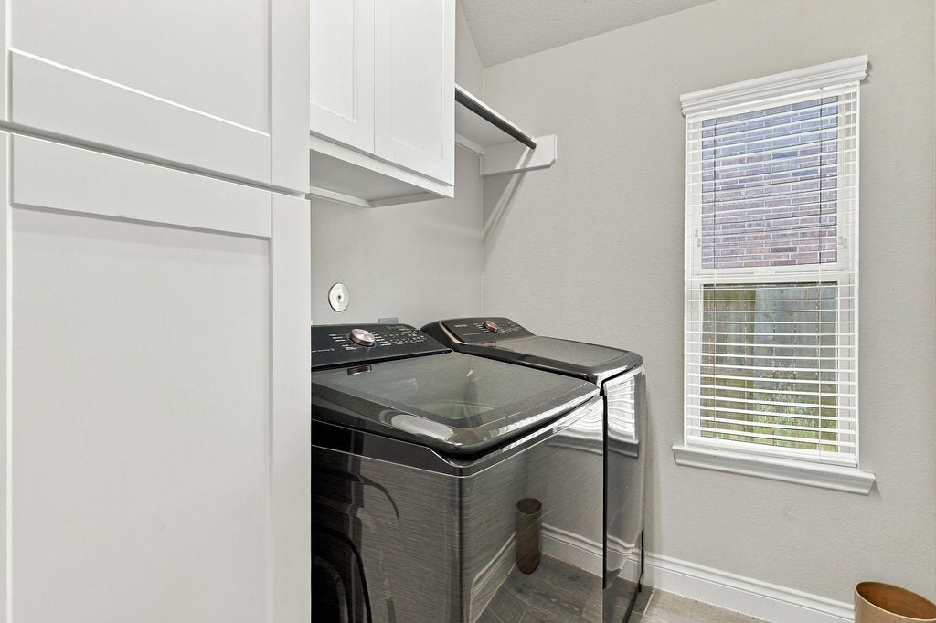 6914 Red Oak Drive, Katy, TX 77493 A bright, functional laundry room featuring modern appliances, ample cabinetry, and natural light from a large window.
