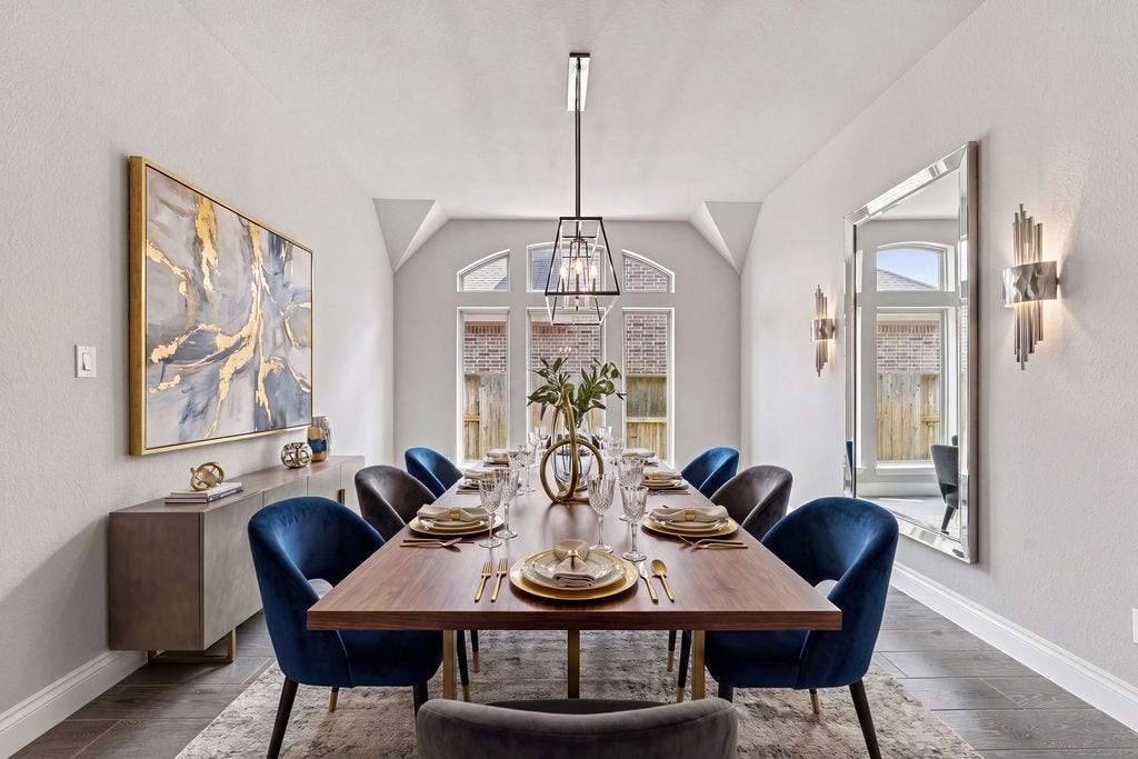 6914 Red Oak Drive, Katy, TX 77493 Elegant dining room featuring a spacious wooden table with plush blue chairs, accentuated by modern artwork and a large decorative mirror.