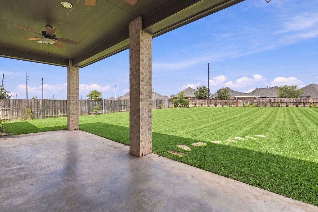 6914 Red Oak Drive, Katy, TX 77493 Spacious covered patio overlooking a large, beautifully manicured backyard, perfect for outdoor gatherings and relaxation.