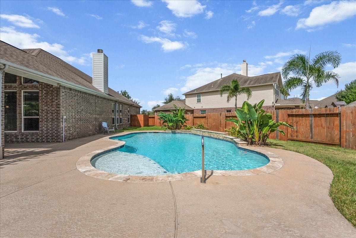 Enjoy a refreshing escape in this backyard oasis featuring a sparkling pool surrounded by a spacious patio, perfect for relaxation and entertaining on an oversized cud-de-sac lot.