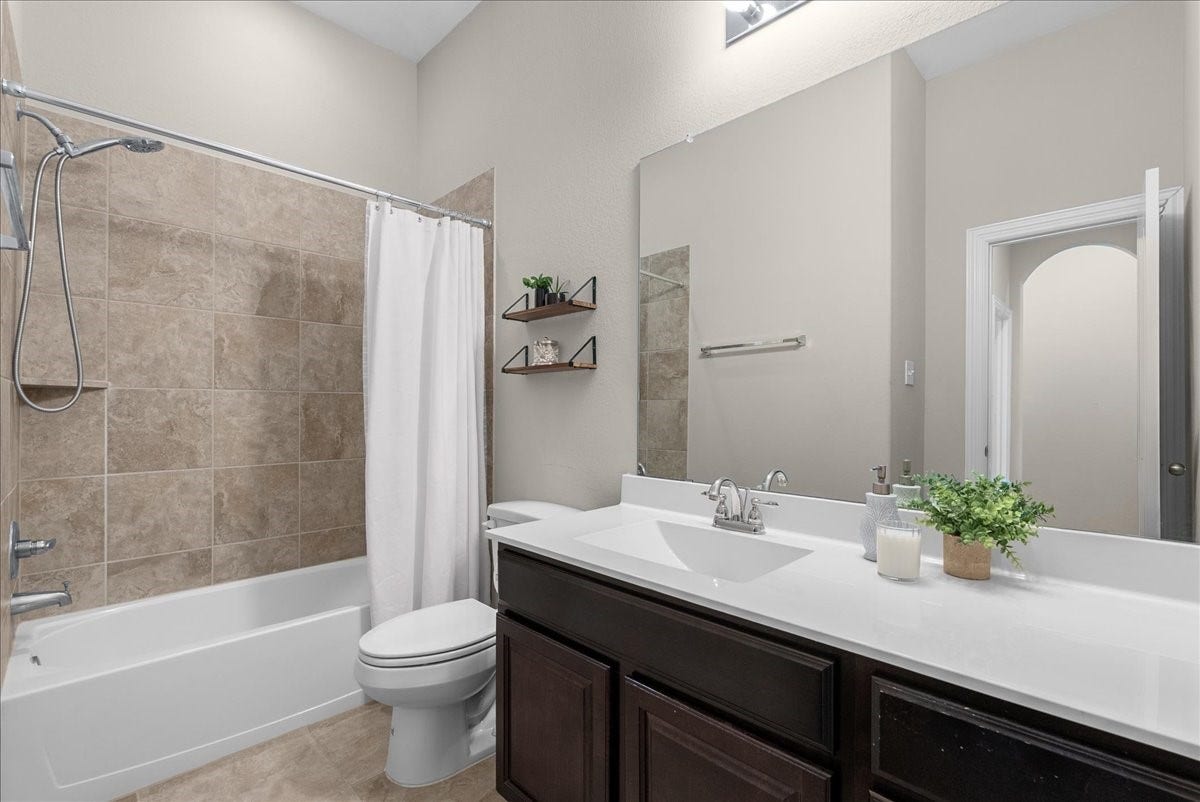 Elegant guest bathroom featuring a sleek vanity with a large mirror, a tiled shower-tub combo, and modern fixtures, complemented by warm neutral tones and stylish shelving.