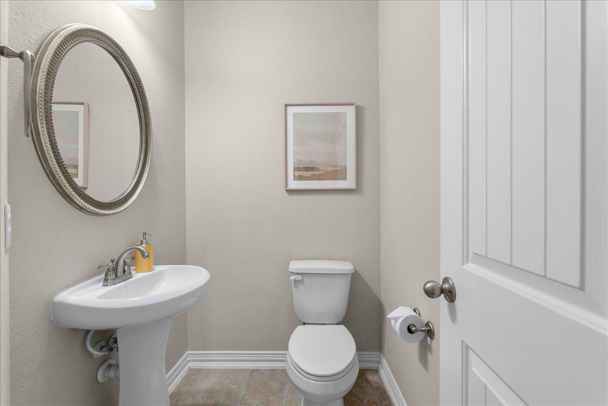 Charming powder room featuring a pedestal sink, elegant round mirror, and tasteful artwork, offering a fresh and inviting atmosphere for your guests and family to enjoy.