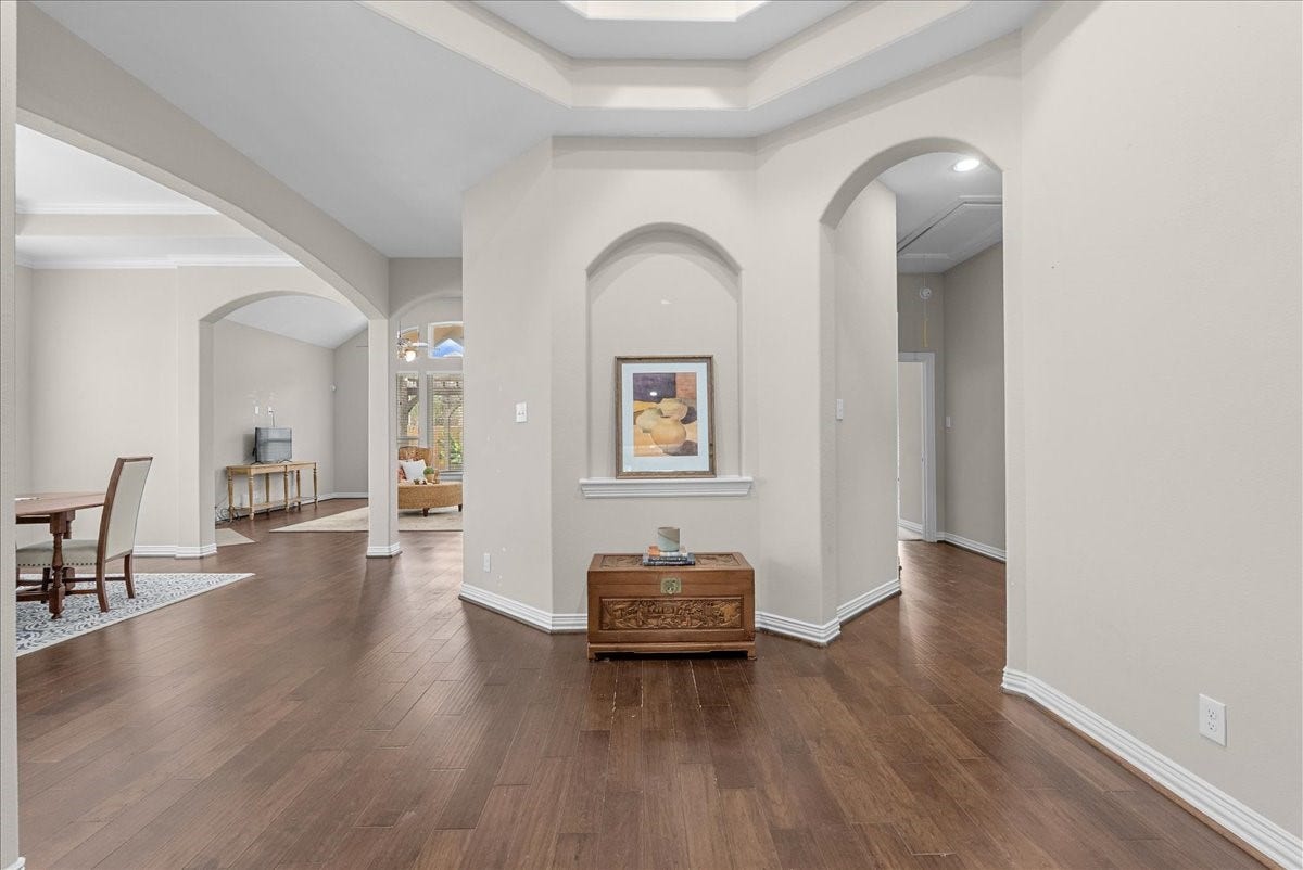 Elegant entrance with beautiful engineered hardwood floors and archways leading to spacious living and dining areas to the left and primary suite to the right with a perfect little powder room for your guests.
