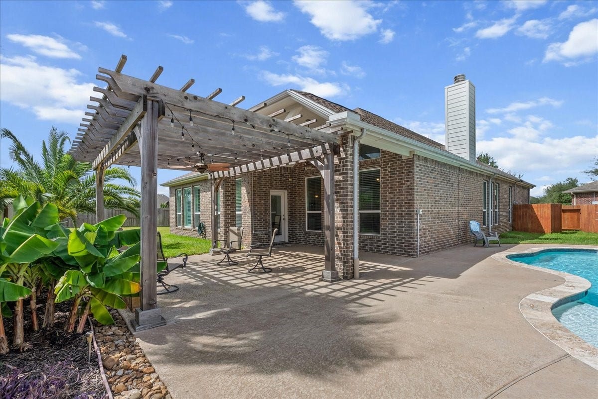 Experience outdoor living with a spacious patio featuring a charming pergola, overlooking a sparkling pool and lush greenery.  So many possibilities!