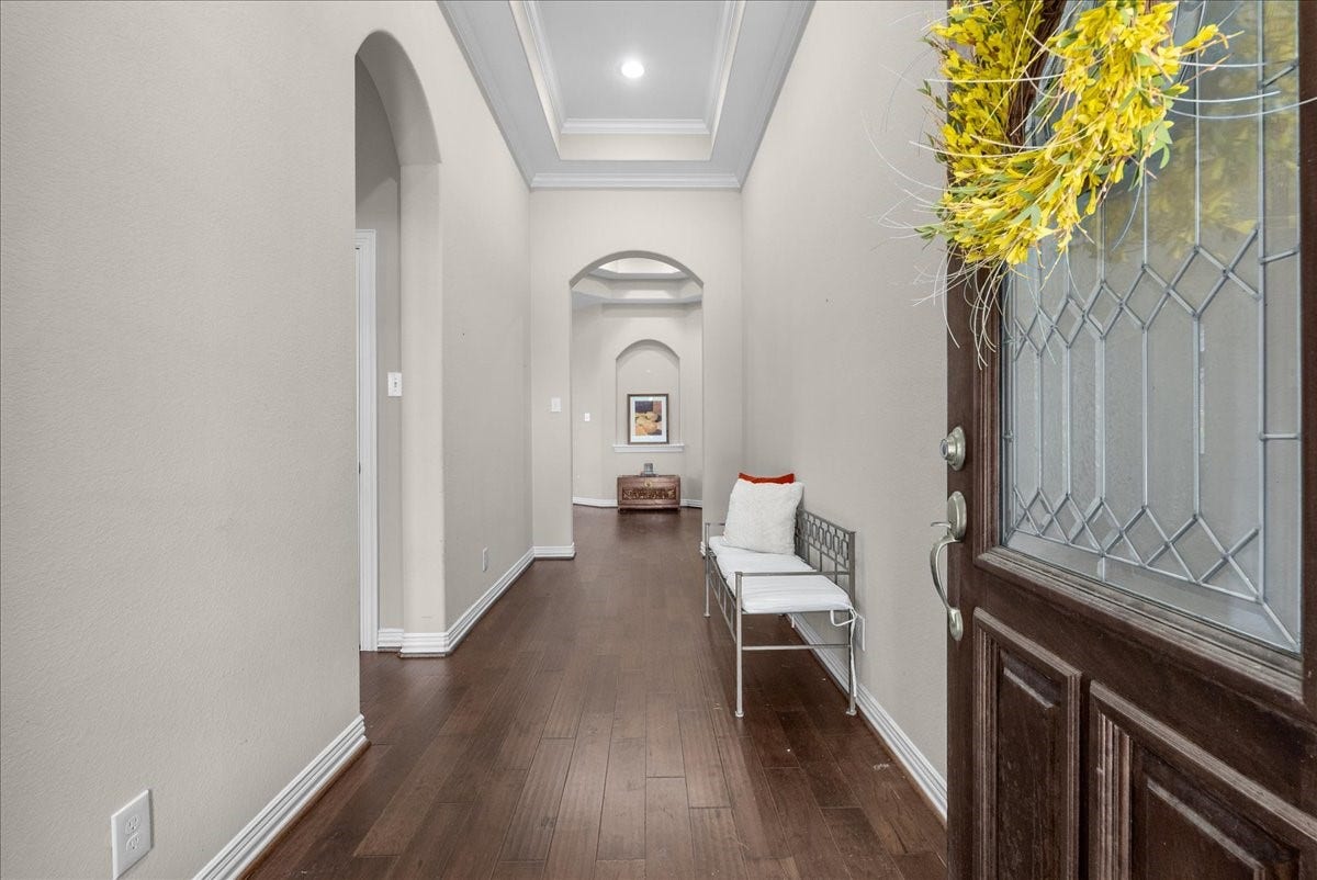 Inviting entryway with elegant hardwood floors, high ceilings, and tasteful archways, offering a warm and welcoming first impression.