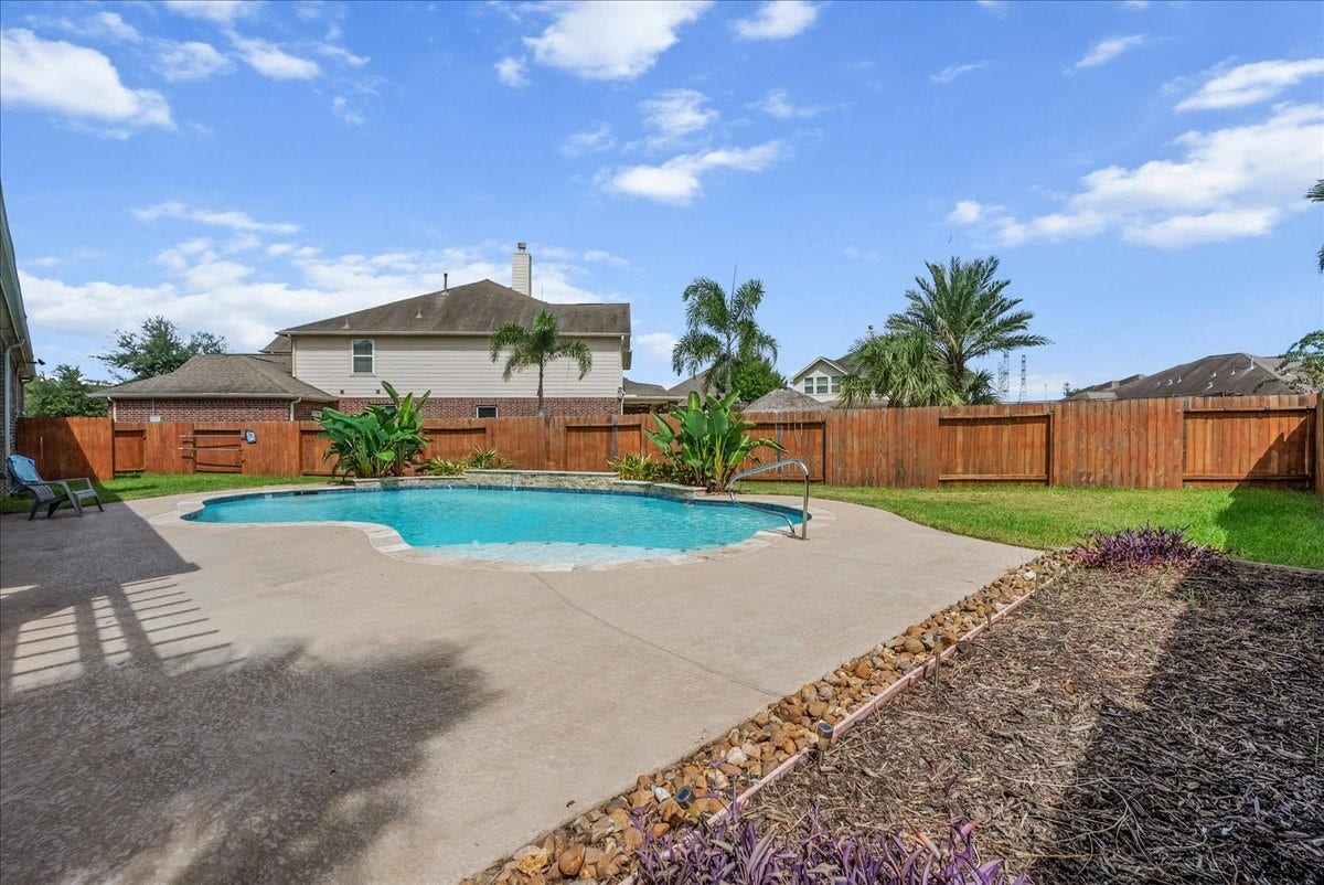 A spacious backyard oasis featuring a sparkling pool surrounded by a well-maintained deck and privacy fencing, perfect for relaxation and entertaining.