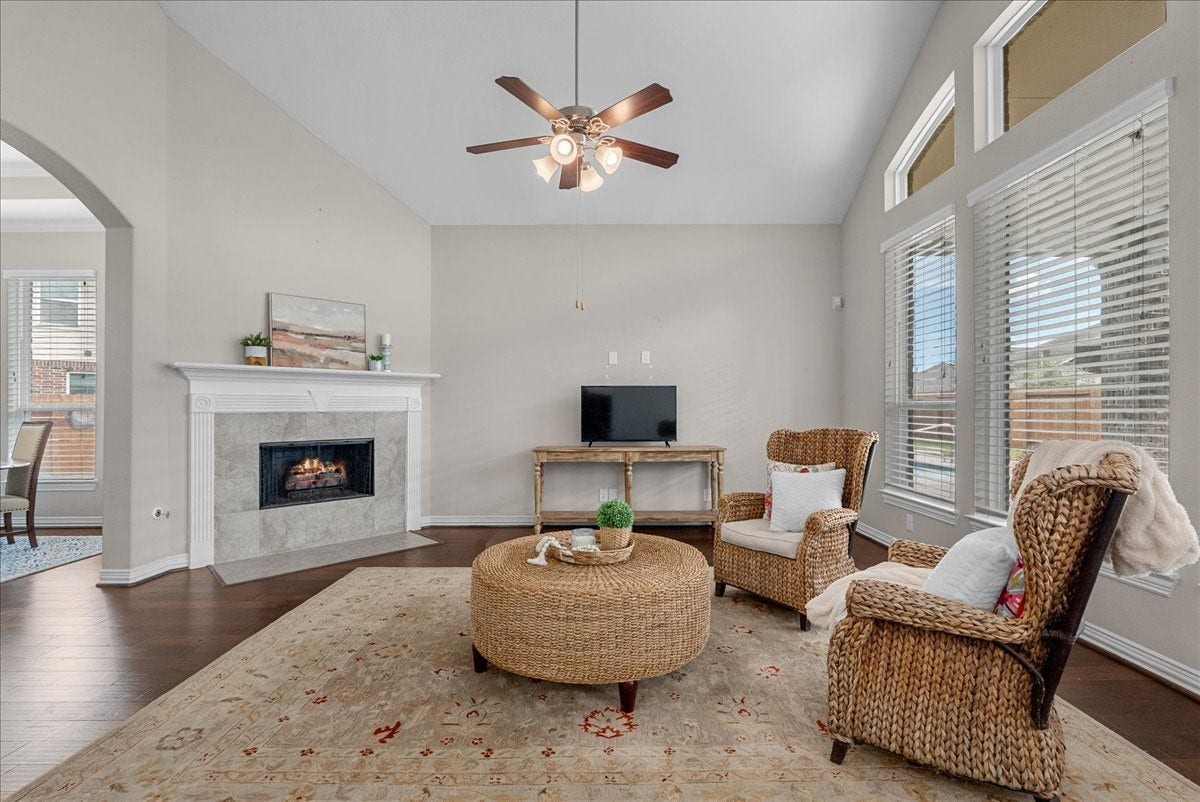 While you are in the kitchen, this is your view of the living room with a cozy fireplace, high ceilings, and abundant natural light from large windows.