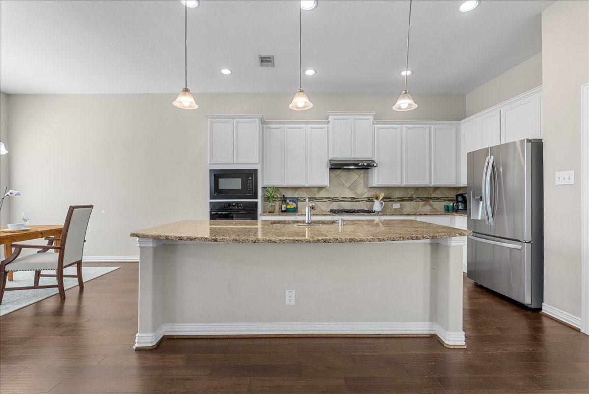 Spacious kitchen with a large granite island, stainless steel appliances, and elegant pendant lighting, perfect for entertaining and family gatherings.  Just picture your bar stools lined up here for your guests and children to enjoy.