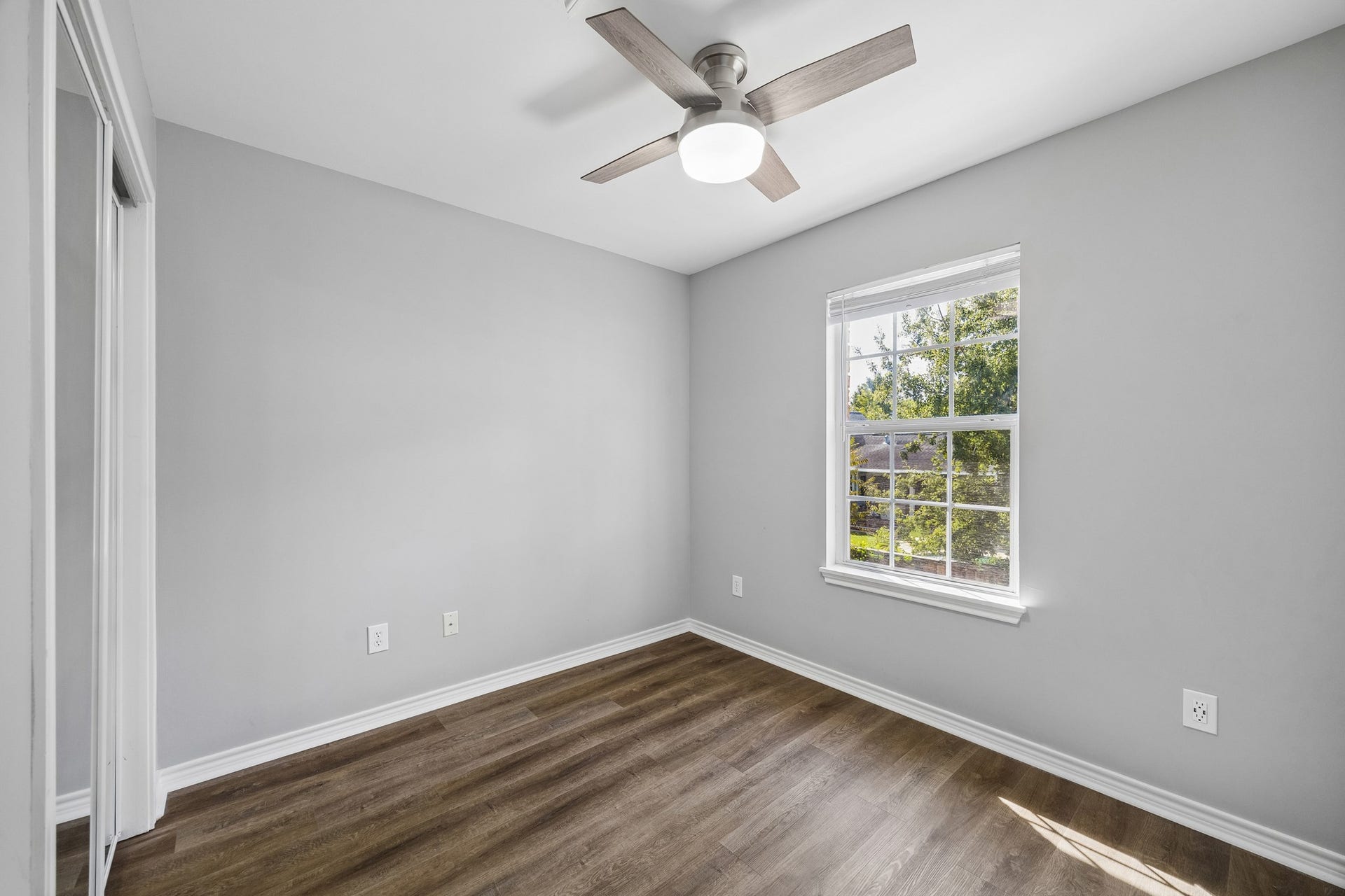 1439 Waverly Street, Houston, TX 77008 Garage apartment bedroom with engineered wood flooring, a ceiling fan, and natural light from a large window.