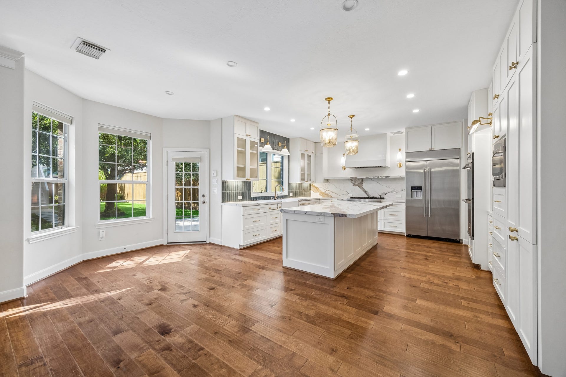 1439 Waverly Street, Houston, TX 77008 Renovated kitchen with a large center island, quartz countertops and backsplash, custom cabinetry, and stainless steel appliances, opening to the spacious living area.