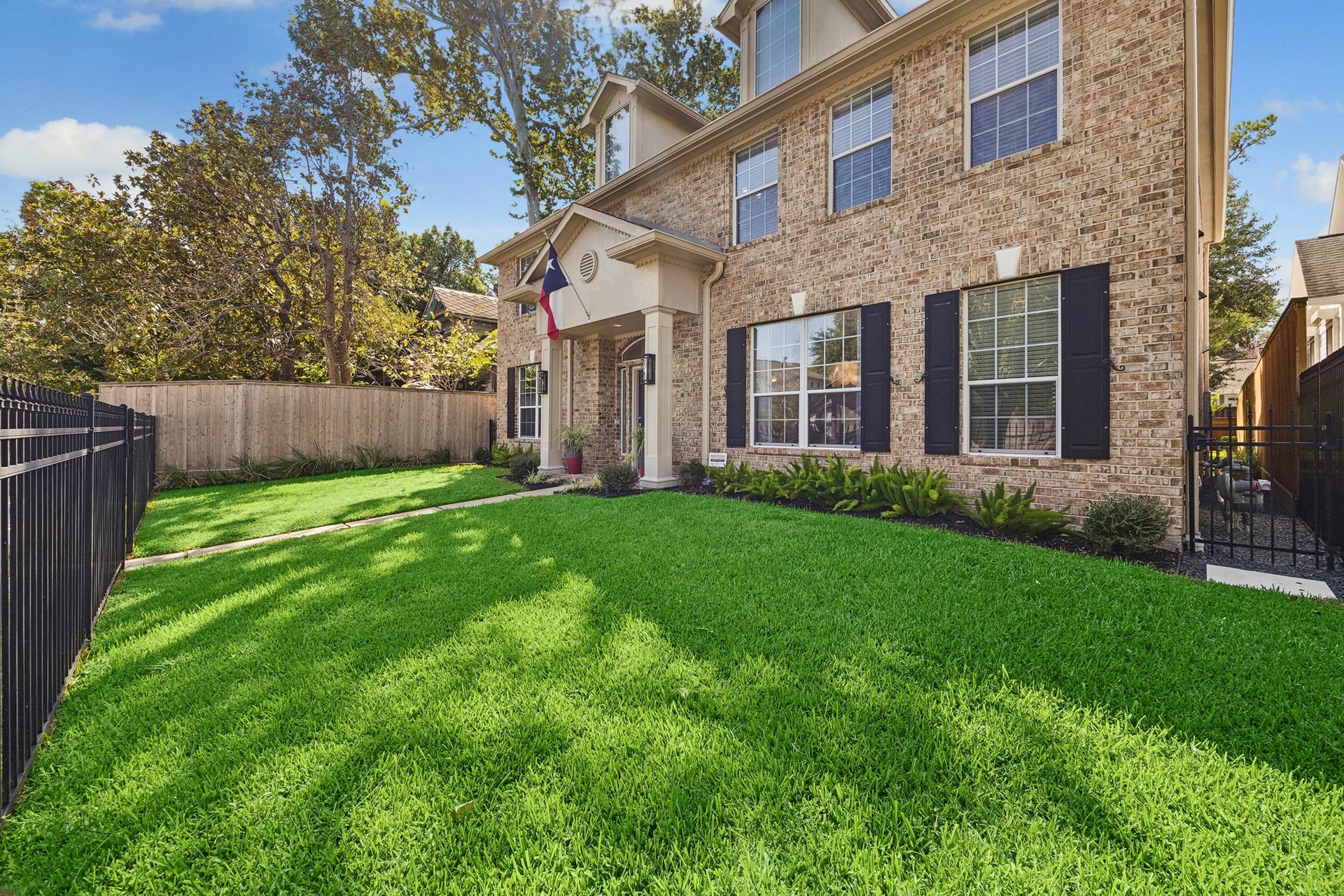 1439 Waverly Street, Houston, TX 77008 Fully fenced front yard with a lush lawn, mature trees, and established landscaping, creating a welcoming approach to the home.