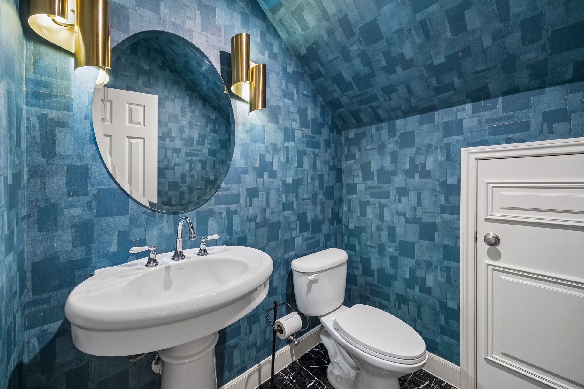 1439 Waverly Street, Houston, TX 77008 Stylish powder room featuring bold blue textured wallpaper, a statement round mirror, and modern brass lighting.