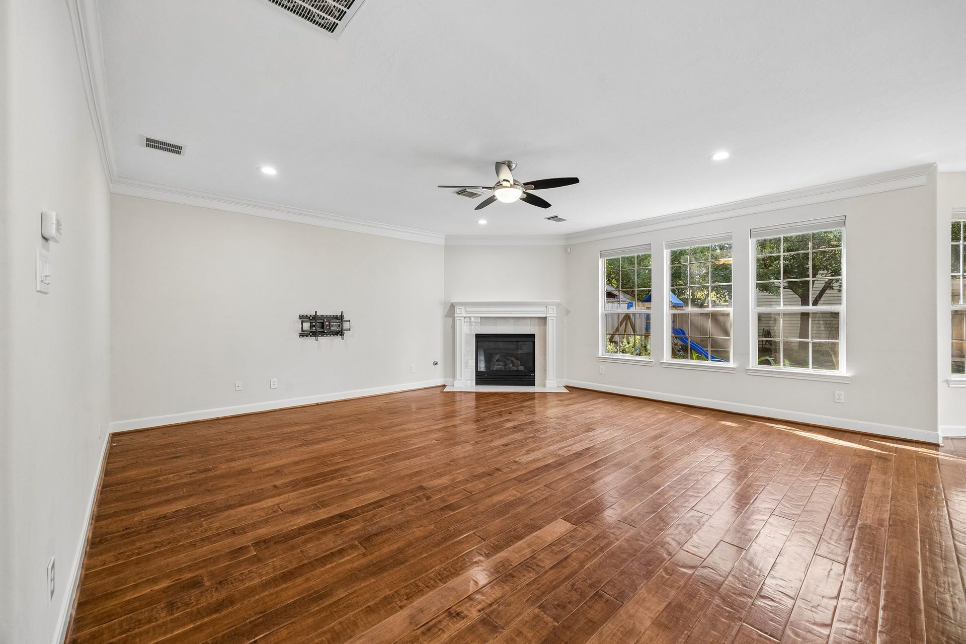 1439 Waverly Street, Houston, TX 77008 Spacious living area with rich wood floors, a gas-log fireplace, and abundant natural light from large windows overlooking the backyard.