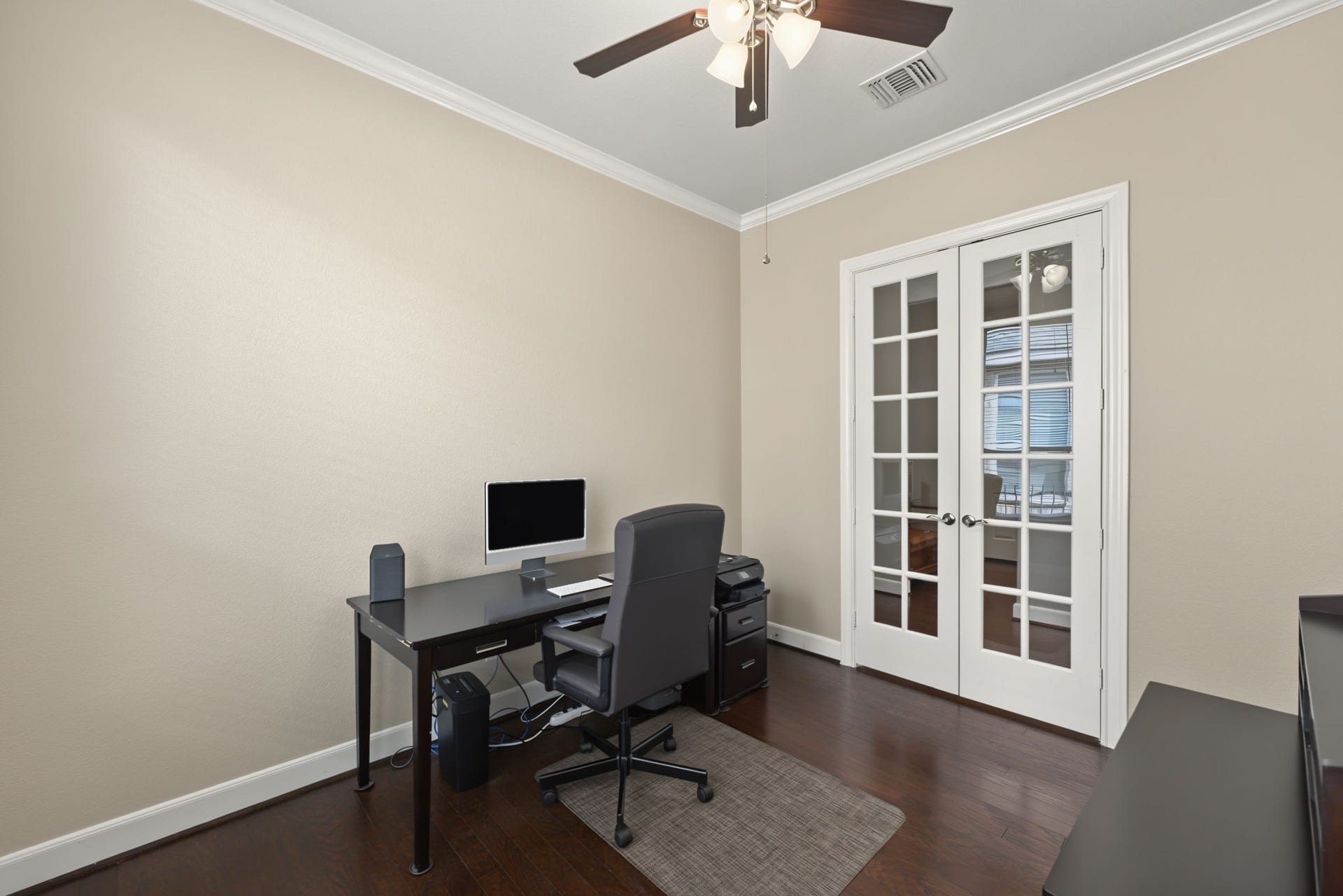 Home office/study has crown molding and ceiling fan.
