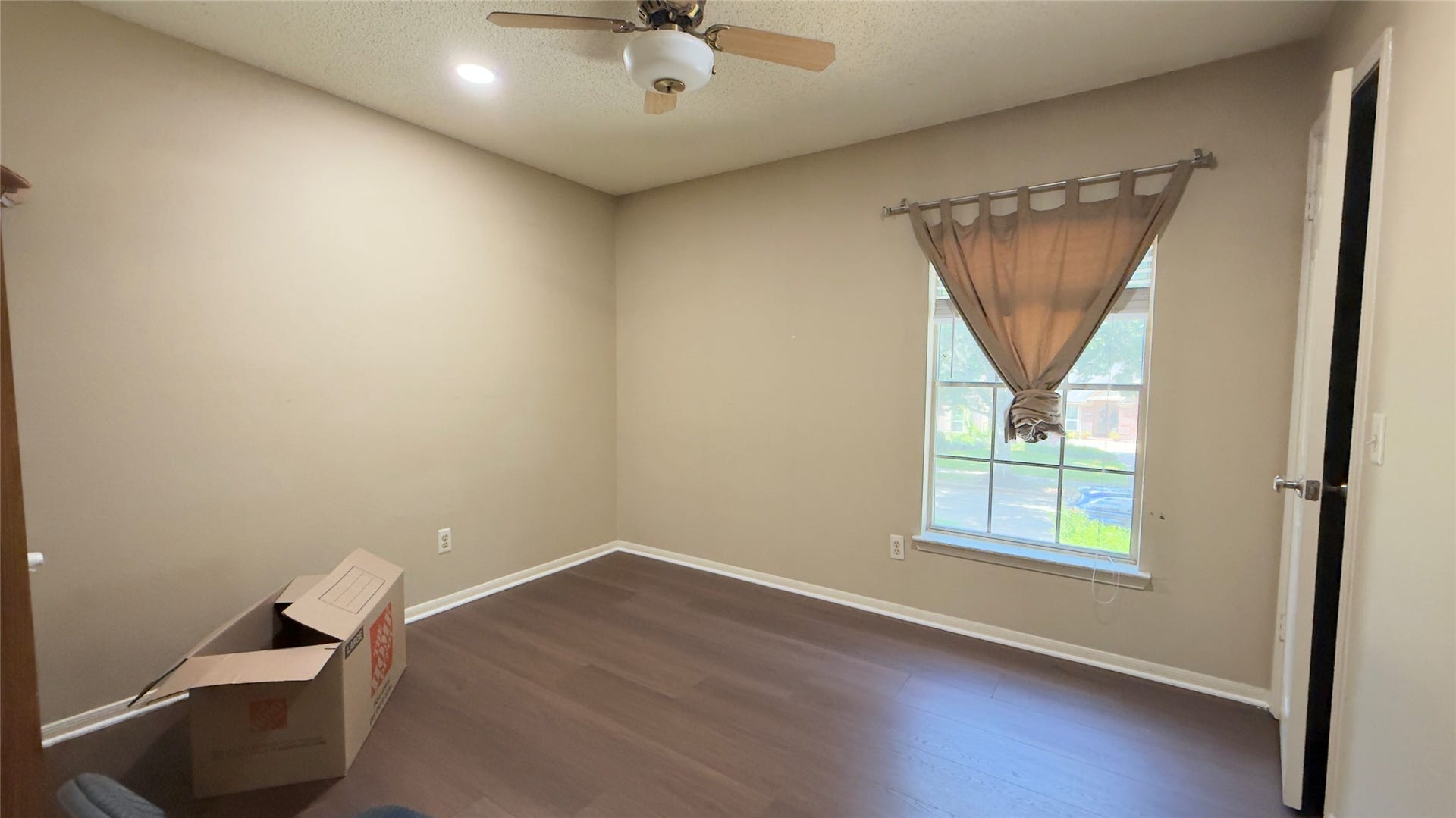 4119 King Cotton Lane, Missouri City, TX 77459 Cozy room #1 with warm neutral walls, rich wood flooring, and a ceiling fan, complemented by natural light from a window with simple drapery.