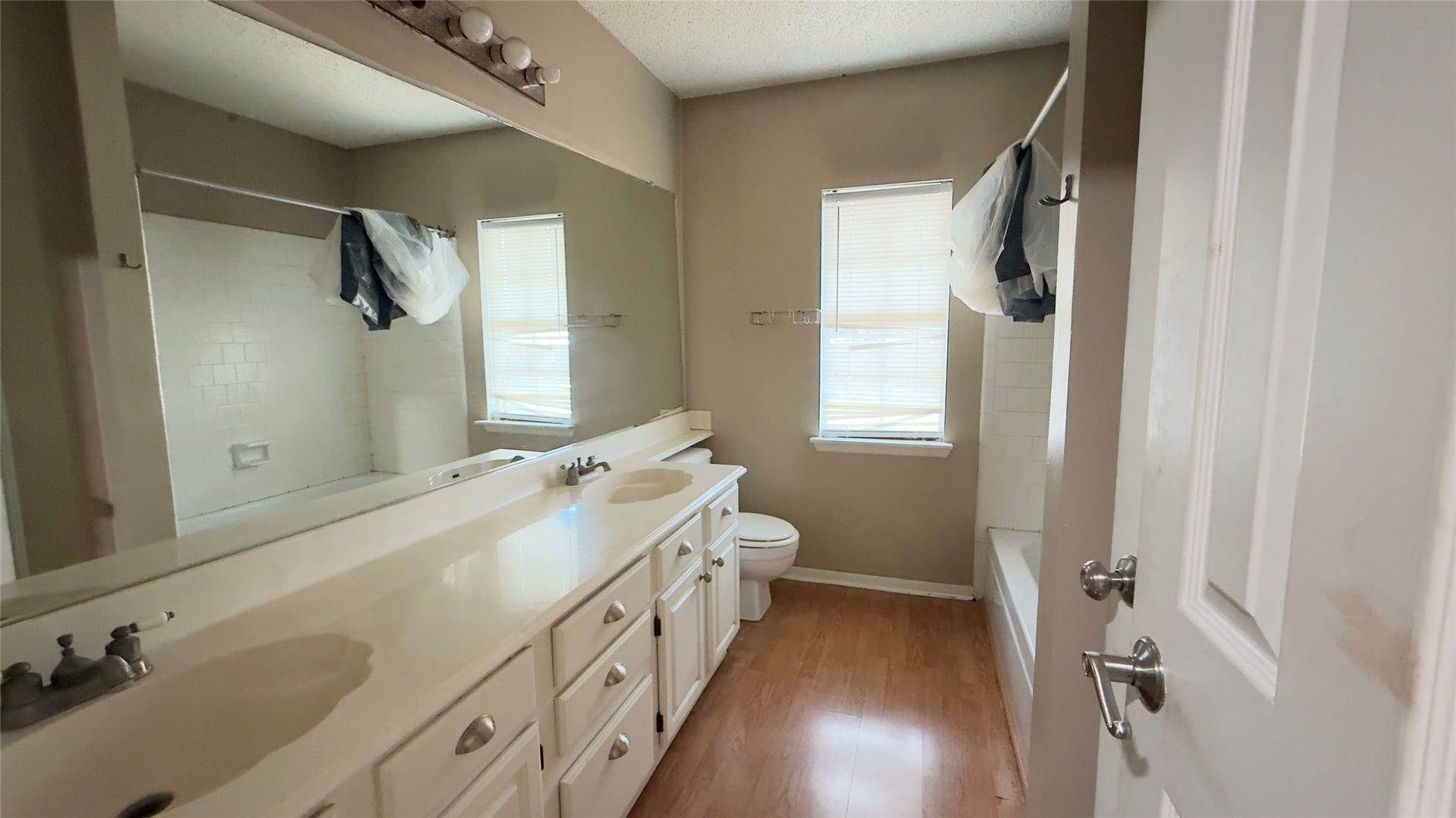 4119 King Cotton Lane, Missouri City, TX 77459 Spacious bathroom with a double vanity, large mirror, and ample storage. Natural light streams in through two windows, highlighting the inviting tub and shower area.