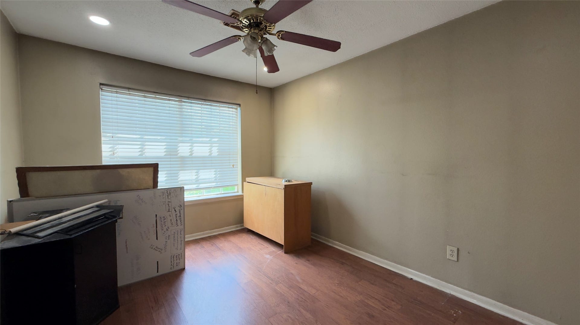 4119 King Cotton Lane, Missouri City, TX 77459 Cozy room featuring warm wood flooring, a ceiling fan, and ample natural light from a large window, ideal for a home office or small bedroom.